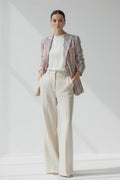 Woman wearing a striped Linen blazer and white pants on a plain background