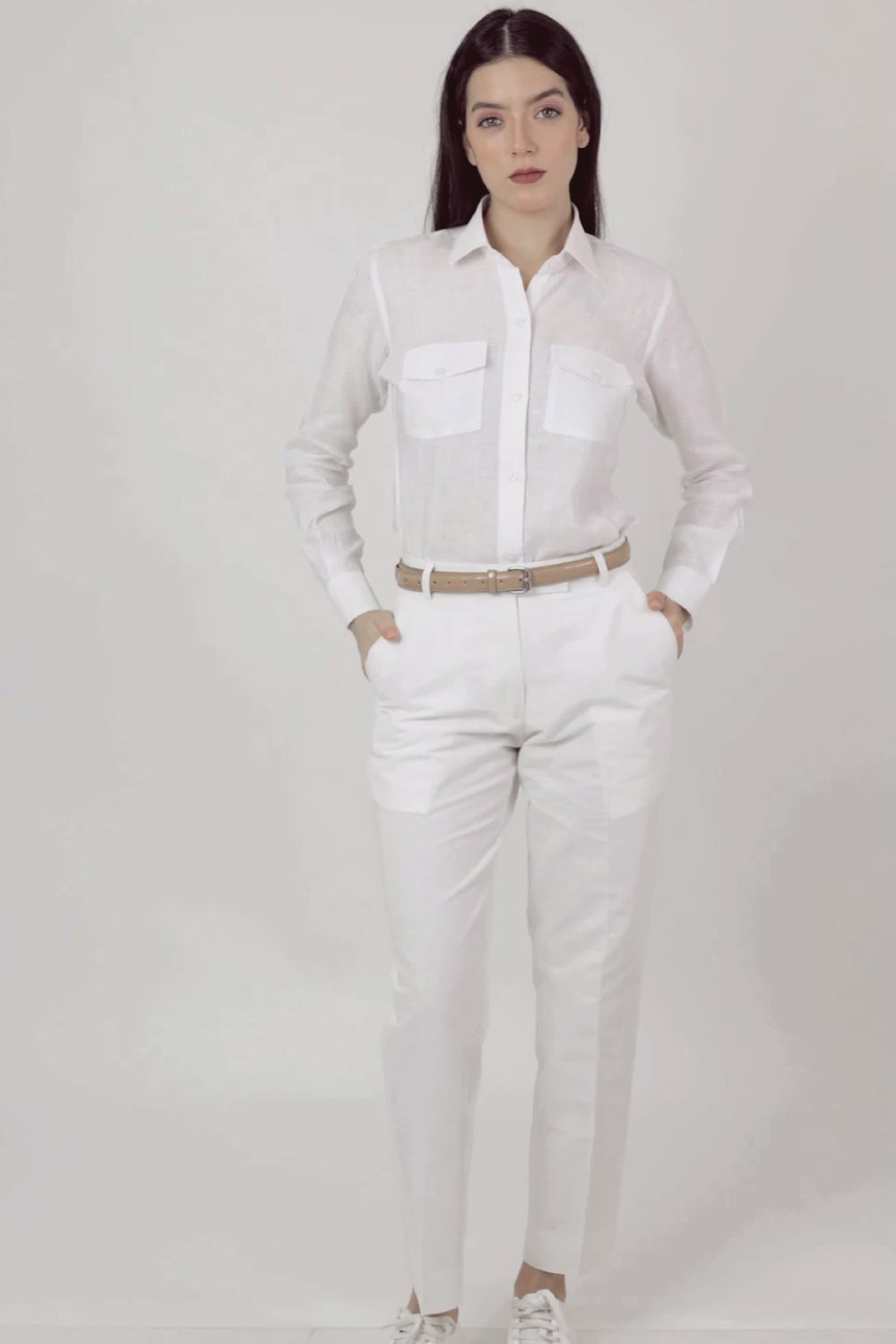 A pair of white women's hemp trousers with a belt, slanting front pockets, and jetted back pockets, featuring a hook and bar closure at the waistband and a zip fly.