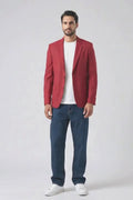 A man modeling a red linen blazer over a white t-shirt, blue jeans, and white sneakers, standing against a plain white studio background.