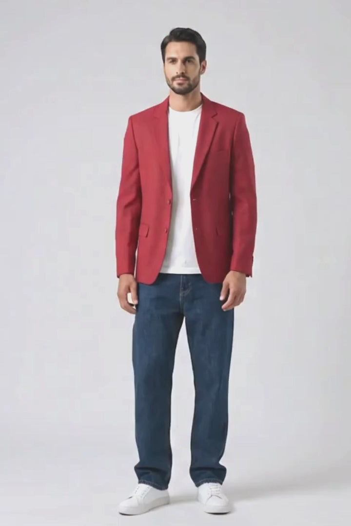 A man modeling a red linen blazer over a white t-shirt, blue jeans, and white sneakers, standing against a plain white studio background.