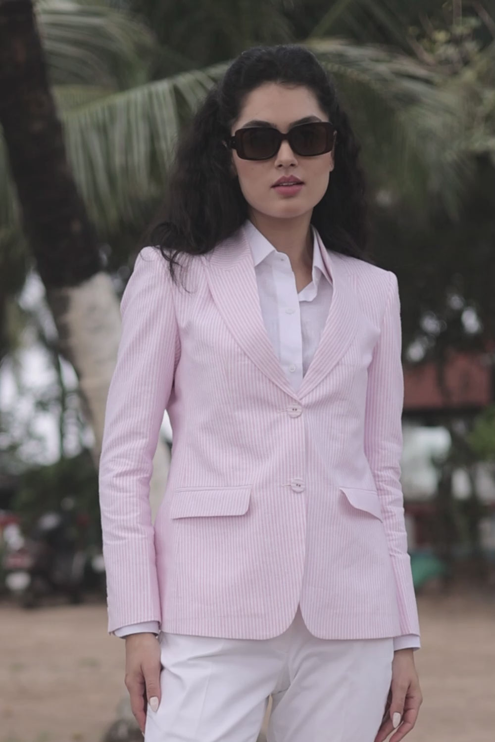 Woman wearing a light pink blazer with a subtle pattern on a white 